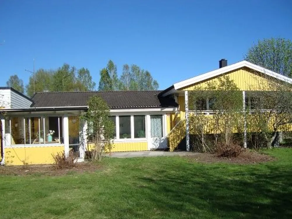 A yellow villa with some trees in the backyard.