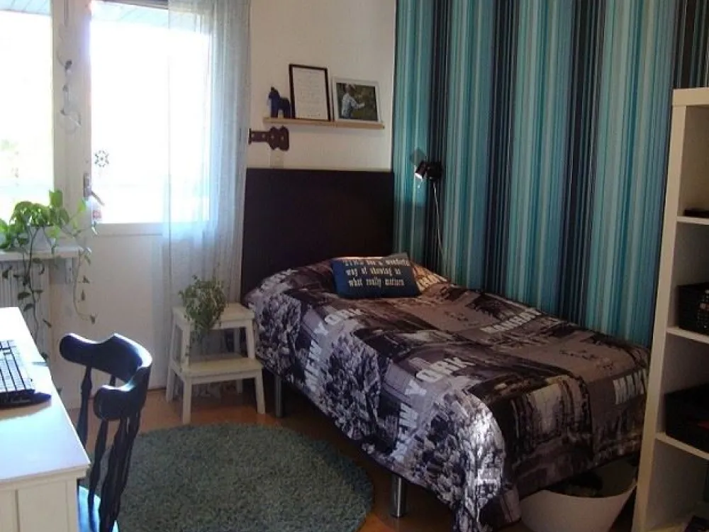 A bedroom with a single bed and a writing desk.