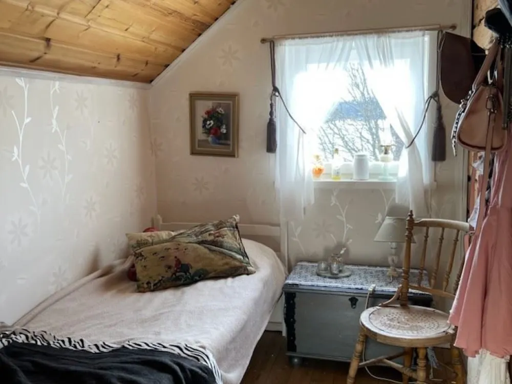 Single bed with a chest and a chair next to the bed.